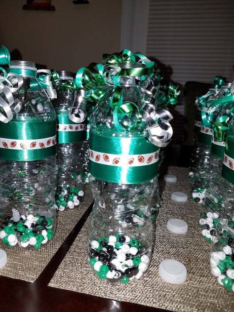 Football Cheer Shaker. All you need it's empty water bottles, ribbon, glue and beads. Spirit Shakers Water Bottle, Cheer Noise Makers Diy, Cheer Buckets Ideas, Cheer Spirit Sticks, Cheer Decorations, Cheer Buckets, Peewee Football, School Spirit Posters, Cheer Banquet