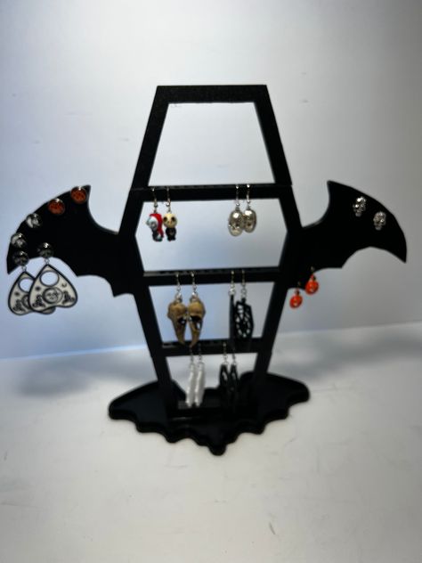 "3D Printed Coffin Shaped Earring Holder with Bat Wings. Holds   - 18 Pairs of Drop Style Earrings  - 30 Pairs of Post Style Earrings Bottom Base has a Reservoir for any extra small items you need to keep from being lost. Stand Measures: 12 1/2\" Tall x 13 1/2\" Wide x 4 3/4\" Deep Disclaimer The 3D printing process is not perfect so there may be blemishes in the surface finishes and visible layer lines. Some items may not be exactly as pictured and as much as we try to take accurate photos, the color may be slightly different than viewed on your screen. We do our best to make sure all 3d prints are free from blemishes, however there may be some slight imperfections from the 3d printing process. Sometimes the printing may leave a slightly layered surface and is custom to each individual pa Gothic Cricut Projects, 3d Printed Necklace Holder, 3d Printed Gothic, Goth Earring Holder, Gothic Halloween Plug Earrings, Bat Hoop Earrings, Gothic Earrings, Goth Home, Goth Decor