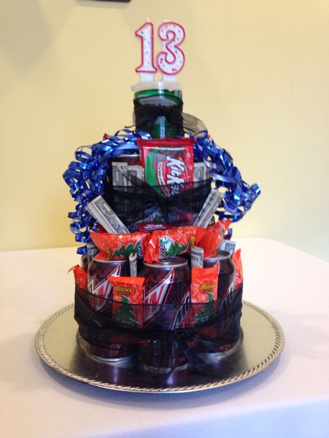 Birthday cake of his or her favorites.... Do it yourself Money cake 12- pack soda cans 1- bag Candy 3-4 candy bars 10-20 dollars$$$ i used 13 ones  -origami bows were cute but I couldn't make them- YouTube has tutorial video  1- roll wire or unwired ribbon your color choice - Hot glue gun, tacky stuff and two sided tape Plastic charger plate from hobby lobby for the base       Start stacking cans about 5-6 on bottom tier-  and use tacky stuff or hot glue to stick cans to each other AND to glue  the BOTTOM OF CANS charger so it doesn't slide off !!!  Then stack next level with 3 -4 cans glue the same.  Then plan out where u want candy placed- may need to add your ribbon around cans at this point.... Then tack candy on and your $$$$$ finish off with candles on top and curly bows Tack Candy, Candy Place, Money Cake, Money Gifts, 20 Dollars, Charger Plate, Candy Bars, Gift Cake, Money Gift