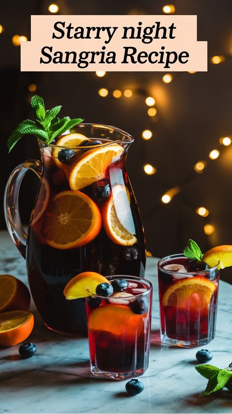 Pitcher and glasses of sangria with oranges, blueberries, and mint, set against twinkling lights. Sangria Easy Recipe, Sangria Holiday Recipes, New Years Sangria Recipes, Nye Sangria, New Year’s Eve Sangria, New Years Sangria, Sangria Recipes For A Crowd, Cranberry Bellini Recipe, Sangria Recipes Red