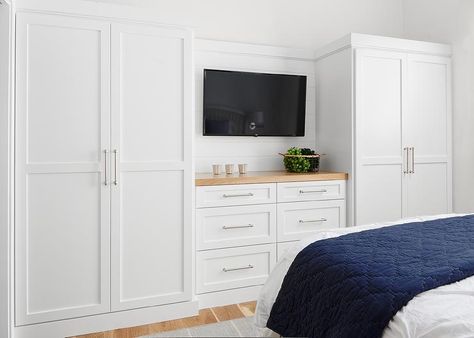 White built-in wardrobes flank a built-in dresser accented with a wood top and fixed beneath at flat panel television. Built In Dresser In Bedroom Chest Of Drawers Closet Ideas, Bedroom Storage With Tv, Bedrooms With Built In Storage, Built In Closet Tv Bedroom, Built In White Wardrobes, Wardrobe Master Bedrooms Built Ins, Where To Put Wardrobes In Bedroom, Bedroom Built Ins With Tv, Wardrobe With Built In Tv