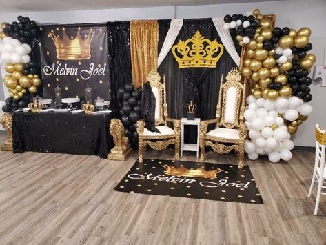 Glamorize your party setup with a regal backdrop by stylishly draping black, gold, and silver sequin curtains and further beautify it with mighty bunches of dazzling black, gold, and white balloons. Moreover, dress up the sweet table with a black sequin tablecloth and arrange trays, cake stands, and gold crown cake toppers on the table for a sumptuous display. Also, place an additional crown topper in between the two royal chairs using a small white table for an imperial appeal. Black And Gold King Theme Party, Small White Table, Gold Crown Cake, White Small Table, Gold Crown Cake Topper, Event Decor Ideas, Sequin Curtains, Party Decorations Table, Black And Gold Theme