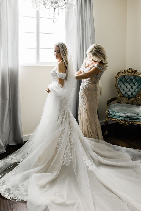 Mother of the bride helping bride get ready in hotel room , bride in elegant white fit and flare wedding gown Wedding Picture Ideas With Mom Mother Of The Bride, Mother And Bride Getting Ready, Wedding Photo Bride Getting Ready, Mother And Bride Photo Ideas, First Glance Wedding Pictures, Must Have Getting Ready Wedding Photos, Mother And Bride Wedding Photos, Bride Getting Dressed Photos, Wedding Day Photos Family