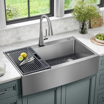 The Delta Lenta Stainless Steel Farmhouse Sink is designed with clean lines and a curved apron front that creates a natural kitchen centerpiece with a clean contemporary aesthetic. Ideal for retrofitting, the top mount design installs as a drop-in sink with any countertop material. Heavy-duty TRU16 gauge stainless steel and SatinSheen finish offers lasting durability and easy maintenance. The sink comes with a grey silicone bottom grid that helps protect the sink surface and a matching over-the- Drop In Stainless Steel Kitchen Sink, Stainless Farmhouse Sink Kitchen, Apron Front Sink Farmhouse, Kitchen Sinks And Faucets 2024, Farm Style Kitchen Sink, Over Mount Kitchen Sink, Drop In Sink Kitchen, Kitchen Sink And Faucet Ideas, Metal Farmhouse Sink