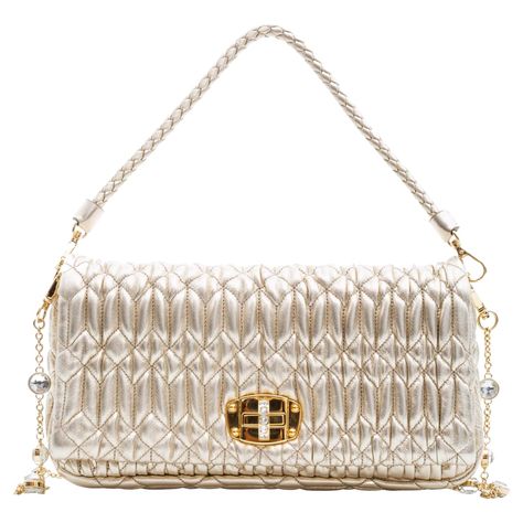 This feminine classic Miu Miu bag is made from the fashion house's signature texture cut from nappa leather with cloquet craftsmanship. The bag features two removable straps including one gold chain shoulder strap with synthetic crystal embellishments and a braided leather top handle strap. Also featuring a synthetic crystal clasp, cotton satin lining and a gold logo applique on the front. COLOR: Beige neurals MATERIAL: Cloquet Nappa leather ITEM CODE: 5BD417 MEASURES: H 7” x L 11” x D 2.5” DROP Miu Miu Purse, Miu Miu Bag, Togo Leather, Kelly Bag, Best Bags, Vintage Louis Vuitton, Gold Logo, D 2, Womens Purses