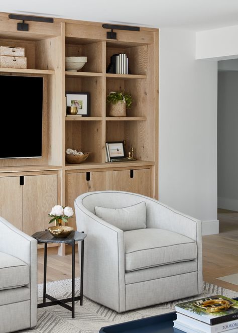 Open shelf white oak entertainment center, with a pair of swivel chairs in ash grey linen, geometric stone end table, and graphic wool rug. White Oak Millwork, White Oak Built In Tv Cabinet, White Oak Entertainment Center, White Oak Bookcase, White Oak Built In Bookshelves, White Oak Office Built In, White Oak Built In, Entertainment Center Built In, Tv Built Ins