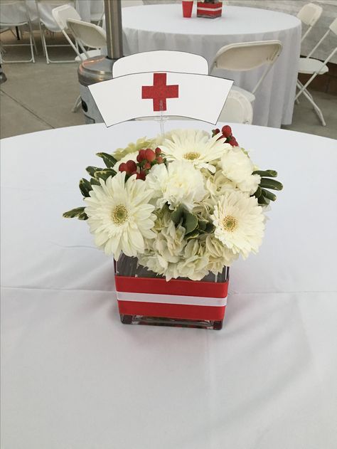 Red and white flowers for nurse graduation theme party! Nurse Flower Arrangement, Nursing School Graduation Party Centerpieces, Nursing Party Centerpieces, Nurse Graduation Backdrop, Retirement Party For Nurse, Nurse Pinning Ceremony Decorations, Nurse Retirement Party Ideas Decorations, Nursing Graduation Centerpieces, Nursing Centerpieces Graduation