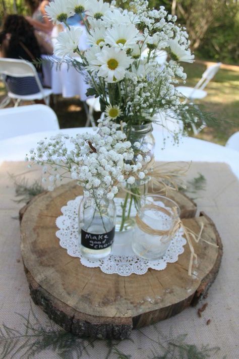 Centerpiece - white tablecloth, burlap square, fern fronds, tree slice, doily, vases with daisies, baby's breath, and candles. We used double sided tape to keep the burlap and doilies from blowing in the wind. Burlap Vases Centerpiece, Doilies Centerpiece Wedding, Wedding Centerpieces With Doilies, Daisy Flower Table Decoration, Wedding Doilies Decor, Doily Centerpiece Wedding, Doily Wedding Decor, Doilies Wedding, Daisy Centerpieces