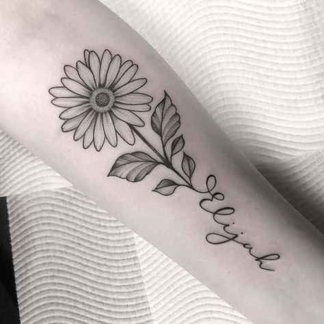 Forearm tattoo traditional black and grey stipple shading daisy with stem forming cursive script ‘Elijah Daisy Tattoo For Mom, Daisy Flower With Name Tattoo, Forearm Daisy Tattoo Women, Daisy Tattoo For Daughter, Daisy Name Tattoo Designs, Flower With Cursive Stem Tattoo, Top Forearm Tattoo Women Simple, Tattoo Flower With Words, Margarita Name Tattoo