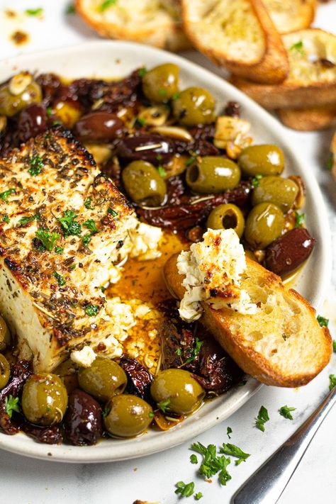 This Baked Feta Appetizer comes together in just minutes with only a handful of ingredients - olives, sun-dried tomatoes, fresh garlic, olive oil, and herbs. Bake it all together with a block of feta cheese until it's warm and creamy then serve with crispy crostini! Baked Feta Appetizer, Feta Appetizer, Baked Feta Recipe, Roasted Olives, Feta Recipe, Baked Feta, Feta Recipes, Garlic Olive Oil, Sun Dried Tomatoes