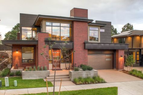 The very modern exterior of the home features red brick and dark brown wood siding that make the boxy design feel welcoming. Dark Siding, Modern Siding, Red Brick House Exterior, Modern Brick House, Exterior Siding Colors, Red Brick Exteriors, Exterior House Siding, Siding Colors, Red Brick House