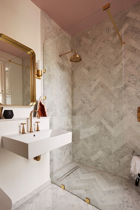 There's something super flattering about painted ceilings - why not give that fifth wall a little love?🌸This pink ceiling matched with these brass assets and marble-effect herringbone tiles creates a modern, minimalist bathroom design that we love!  📸: Victoria Tunstall Herringbone Tile Bathroom, Appartement New York, Chevron Bathroom, Mandarin Stone, Minimalist Bathroom Design, Loft Bathroom, Perfect Bathroom, Small Bathroom Makeover, Marble Wallpaper