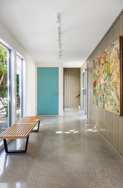 Mid-century foyer featuring a smooth tiles flooring, white and wooden walls, floor to ceiling glass windows and a set of track lighting. Modern Foyer Ideas, Mid Century Foyer, Mid Century Modern Foyer, Mid Century Modern Flooring, Mid Century Modern Entryway, Large Glass Windows, Mid Century Entryway, Mid Century Modern Door, 1950s Home