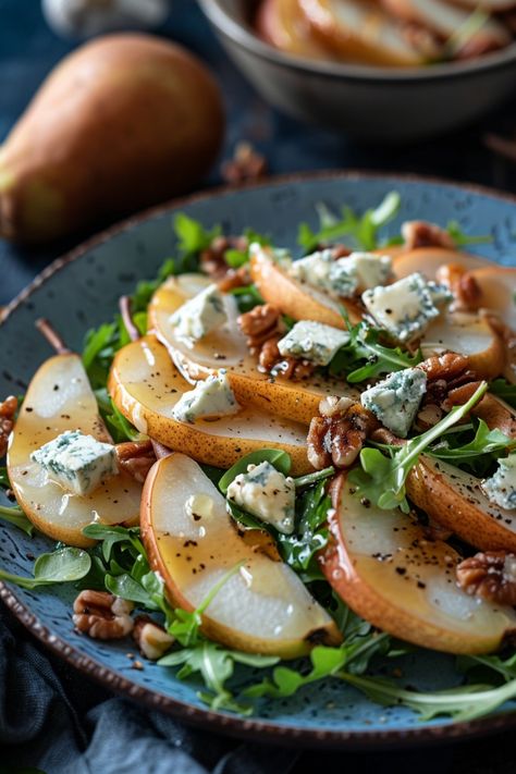 Sliced pear salad with arugula, blue cheese, and walnuts on a blue plate. Pears And Gorgonzola, Gorgonzola Pear Salad, Autumn Dinner Salad, Salad With Pears And Gorgonzola, Baked Pear Salad, Pear Recipes Salad, Pear And Fig Salad, Pear Cheese Salad, Sweet And Savory Salad