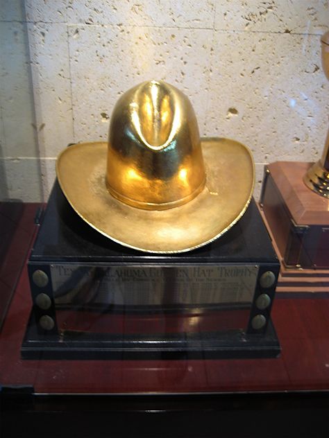 Th Trophy is given to the winner of the Red River Shootout rivalry between the University of Oklahoma Sooners and the Texas Longhorns. The Golden Hat trophy is kept each year by the winning team's athletic department. Red River Rivalry, Oklahoma Sooners Football, Eighties Style, Oklahoma Football, Ou Football, Longhorns Football, Trophy Case, Football Awards, Ou Sooners