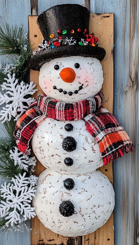 a vertical wall hanging with a festive snowman family design, perfect for holiday decor. The background is a rustic wooden plank, and the snowmen are made from small, white foam or clay balls stacked to form a group. Each snowman has a cheerful expression, with black eyes, orange carrot noses, and colorful ribbon scarves in red, black, and white patterns. The top snowman wears a glittery black top hat, adding a touch of elegance. Easy Snowman Crafts, Wooden Snowman Crafts, Diy Snowman Crafts, Selling At Craft Fairs, Crafts That Sell, Cheerful Expression, Profitable Crafts, Snowman Crafts Diy, Snowman Candle