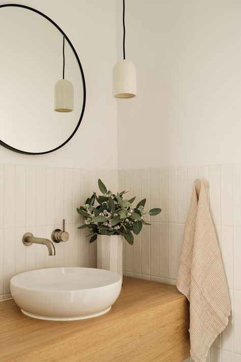 Corner view of a timber bathroom vanity, white vertical tiled splashback and black framed round mirror sitting above a white round sink Nordic Powder Room, Small Splashback Bathroom, Powder Room Splashback, Powder Room White Tile, Vanity Splashback Tiles, Bathroom Ideas Scandinavian Style, Small Bathroom Ideas Classic, Tile Splashback Bathroom Sink, White Vertical Tiles Bathroom