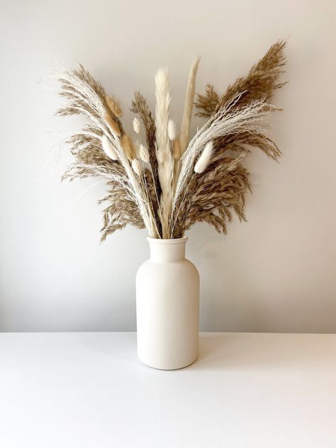 Beautiful natural dried flower arrangement including fluffy pampas and an assortment white/neutral dried flowers. The dried bouquet comes with an option to add a hand painted beige vase. The vase and pampas bouquet together are the perfect addition for any neutral/boho home decor or are ideal as a home gift.  **PLEASE READ** Vase dimensions: 20cm Tall, 10cm Wide.  Bouquet dimensions: approx 45cm tall.  Bouquet contains:  - 3 Stems fluffy natural pampas - 2 Stems white pampas - 2 Stems white misc Pampas Flower Arrangement, Tall Bouquet, Neutral Boho Home, Wide Bouquet, Pampas Flower, Pampas Bouquet, Beige Vase, Vase Beige, Lounge Inspiration