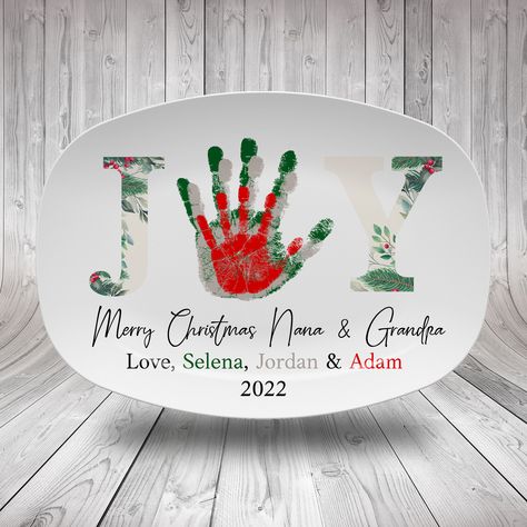 After all these years, isn't it time to give your grandparents something truly unique this Christmas? Whether your grandparents are active, outgoing souls or quiet household legends, this Joy Handprint Platter will definitely please them. We will put their handprints on this Christmas handprint platter so that it could become the only one in this world. HOW TO ORDER: 1. Include your personalization in the personalization box. 2. Add to cart 3. Take a clear picture of (or scan) the handprint, foo Yearly Handprint Keepsake, Christmas Crafts For Kids For Grandparents, Christmas Gifts For Grandparents Diy, Handprint Plate Diy, Christmas Handprint Plate, Christmas Ideas For Grandparents, Handprint Gifts For Grandparents, Christmas Plates Diy Kids, Christmas Plates Diy