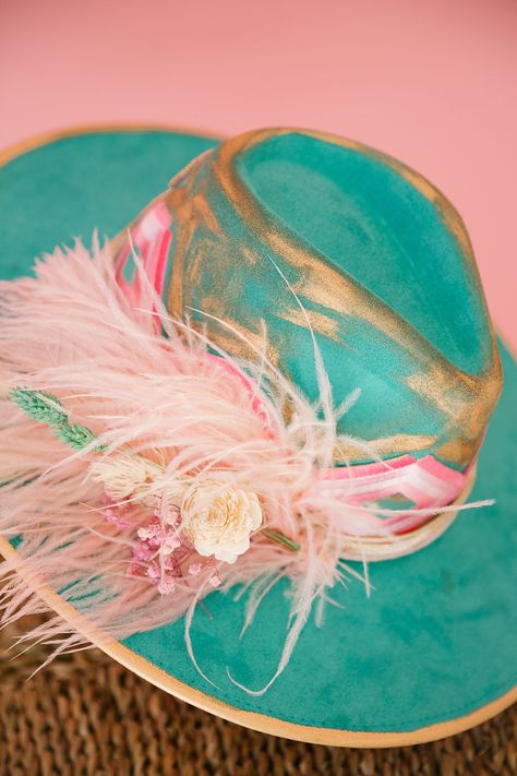 Get ready to wrangle some compliments with The Floral Tennis Rancher Hat! This turquoise beauty boasts gold accents, a striking pink aztec ribbon band, and a pink sequin Tennis patch on the back. Add in a splash of color with the pink feather combo and you've got yourself a truly unique accessory. This hat is ONE OF A KIND, created by our owner Stephanie. To receive item quicker, expedited shipping is available at checkout. Cowgirl Hat Ideas, Painted Hats For Women, Cowboy Hat Crafts, Custom Cowboy Hats, Funny Trucker Hat, Pretty Hats, Judith March, Felt Cowboy Hats, Painted Hats