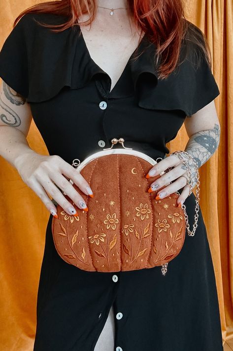 Our absolutely gord-geous Pumpkin purse is here to help you serve fall vibes. The outside is made from soft, velvet fabric. Lightly padded, it has a cuddly, squishy feeling. Not something one normally looks for in a purse, but trust me, you will love it. With delicately embroidered with yellow flowers, stars, and a moon on both sides, this witchy handbag is sure to become part of your regular outfit rotation. #vintagefashion #purses #handbags #fallfashion Witchy Handbag, Cool Purses, Outfit Rotation, Embroidered Pumpkin, Evil Witch, Leather Credit Card Holder, Sewing Box, Autumn Cozy, Sewing Inspiration