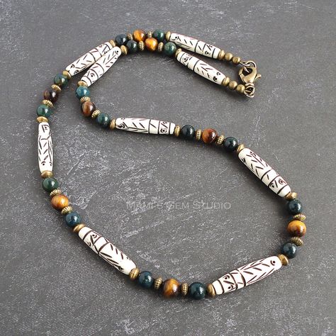 "I made this tribal-inspired necklace for men or unisex, featuring natural bone tube beads with distinctive tribal-style carvings, Bloodstone in deep forest green, and Tiger Eye with moving golden brown sheen. I have also used antiqued brass spacers to add a stylish vintage flavor. It closes with an antiqued brass lobster claw clasp. Lead-safe. The pictures represent a similar item you will receive in quality and shades. Length Options: 18 inches (46cm), 19 inches (49cm), 20 inches (51cm), 22 in Mom Fit Jeans, Mens Beaded Necklaces, Brown Stone, Carved Bone, Inspired Necklace, Dangle Necklaces, Diamond Cross Pendants, Homemade Jewelry, Deep Forest