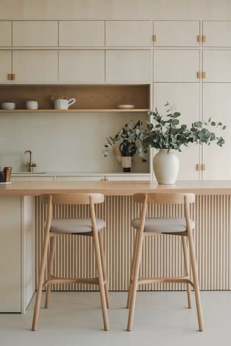 Minimalist kitchen with wooden cabinets, a countertop with two chairs, and a vase with greenery. Japandi Kitchen Small Space, Breakfast Counter Design, Unique Kitchen Island Ideas, Kitchen Island Seating, Japandi Style Kitchen, Japandi Furniture, Minimalist Japandi, Island Seating, Breakfast Counter