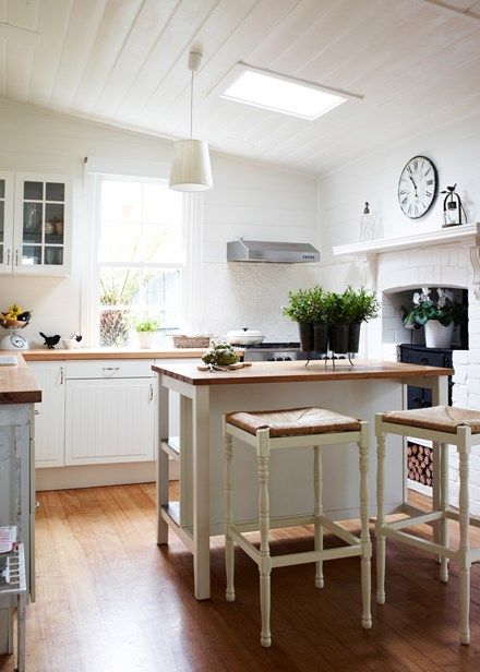 The original wood stove is the only remnant of the old kitchen, which has been given a complete update with cabinets from Ikea and a new paint job in Dulux Antique White USA. An island bench and bar stools acts as a central gathering place for guests. Timber Kitchens, Miners Cottage, Antique White Usa, Wood Counters, Timber Kitchen, Rustic Backdrop, French Provincial Style, Country Cottage Decor, Timber Panelling