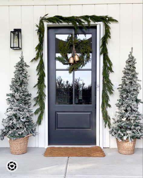 Christmas porch. Porch flocked pencil tree amazon. Basket, jute rug doormat. Black front door and greenery cypress Norfolk garland indoor outdoor. Command hooks, front door wreath and gold bells. Follow my shop @fancyfixdecor on the @shop.LTK app to shop this post and get my exclusive app-only content! #liketkit #LTKSeasonal #LTKHoliday #LTKhome @shop.ltk https://liketk.it/3TKqg Cypress Wreath Front Door, Greenery Around Door Frame Christmas, Christmas Tree Front Door, Porch Post Christmas Decor, Minimalist Christmas Front Porch, Christmas Wreath On Black Door, Simple Front Door Christmas Decor, Christmas Garland Front Door, Norfolk Garland