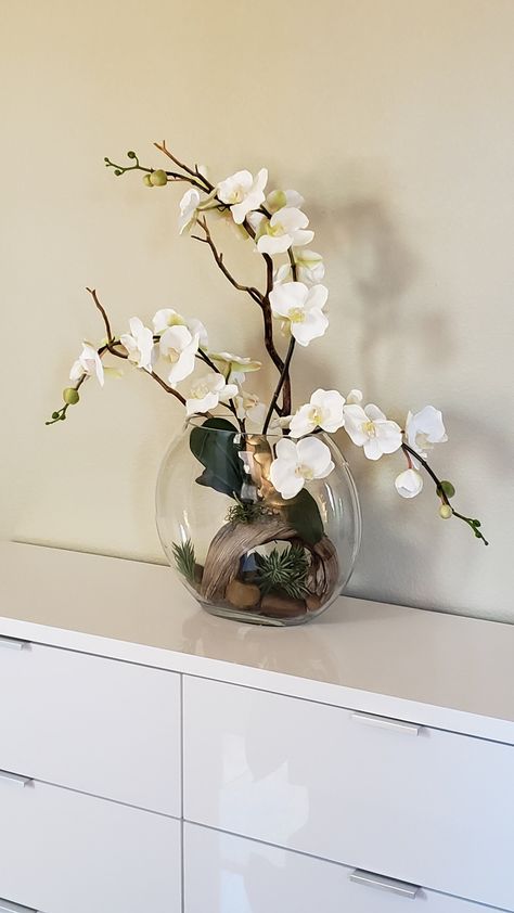 One of a kind orchid arrangement in clear glass vase accented with driftwood, succulents, and rocks. Orchid Arrangements Wedding, Artificial Orchid Arrangement Vase, Orchids In Large Bowl, Orchid Glass Vase, Orchid Driftwood, Orchid Glass Pot, Round Vase, Orchid Arrangements, Clear Glass Vases