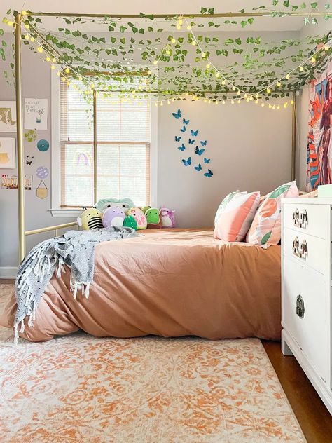 Step into an Enchanted Forest with our Girl's Bedroom Decor Trends! Create a magical space with woodland decor, dreamy colors, and fairy-tale accents. From forest-themed bedding to twinkling lights, every detail sparks wonder. Design a room where her imagination can roam free. Our girl's bedroom design ideas will turn her space into an enchanted forest of charm and delight. #enchantedforest #girlbedroom #bedroomdecor #woodlandaccents #dreamyinteriors Teen Room With Canopy Bed, Preppy Room With Canopy Bed, Vines On Canopy Bed, Ten Year Old Room Ideas, Canopy Bed Lights, Canopy Bed With Plants, Girls Nature Bedroom Ideas, Girls Canopy Bed Ideas, Canopy Bed With Vines