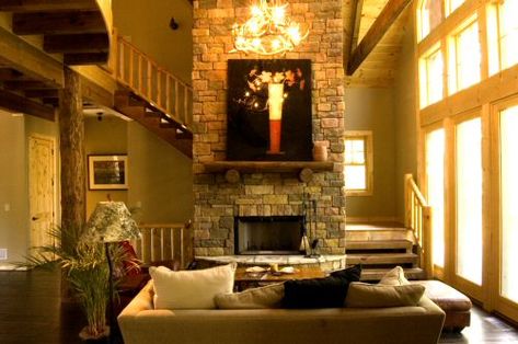 The staircase is behind the fireplace. The hearth of the fireplace repeats the radius detail found throughout the cabin. Stairs Wrapped Around Fireplace, Fireplace By Staircase, Staircase With Fireplace, Stairs Around Fireplace, Staircase Behind Fireplace, Stairs Behind Fireplace, Barn Fireplace, Fireplace Staircase, California Room