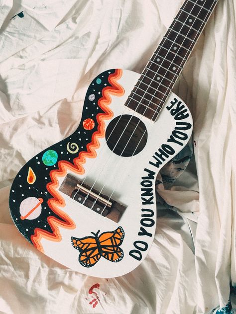 painted the front with my favorite lights up lyric & a butterfly inspired by harry <3 Painted Ukulele Ideas, Painted Guitar Ideas, Painted Guitars Ideas, Painting On Guitar Ideas, Guitar Design Art, Ukulele Painting Ideas, Painting On Guitar, Guitar Painting Ideas, Guitar Art Diy