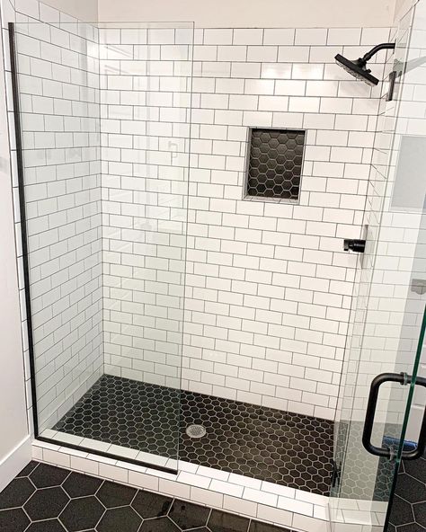 White subway tile shower with glass enclosure is accented by a black hexagon tile shower pan and niche. A black shower kit is mounted to the wall in this black hexagon floor tile bathroom. Black Shower Tile White Floor, Mini Black Hexagon Tile Bathroom, Small Black Hexagon Tile Shower Floor, Subway Tile Shower Black Floor, Black And White Hexagon Tile Shower Wall, Black Matte Hexagon Tile Bathroom, Black Hex Shower Floor, Subway Tile Charcoal Grout Bathroom, Black Tile With Grey Grout