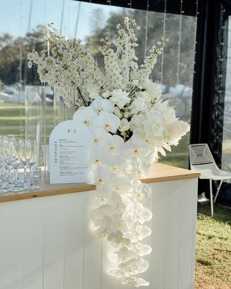 Looking forward to the next wedding season, so we can create some more stunning bar blooms for our beautiful couples. BJ + Joe 🖤 @nedlandsyachtclub Pedestal Wedding Decor, Wedding Bar Design Ideas, Wedding Greenery Ceremony, White Floral Table Arrangements Wedding, Florals On Bar Wedding, Wedding Bar With Flowers, Outside Wedding Bar, Flower Arrangements For Engagement Party, Elegant White Floral Arrangements