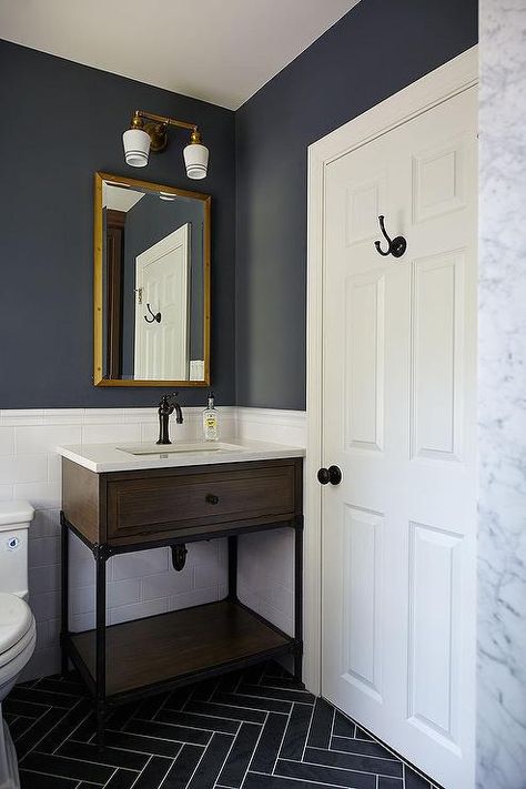 Blue and gray kid's bathroom features upper walls painted dark blue and lower walls clad in white subway tiles lined with a wood and iron washstand and a Restoration Hardware Rivets Medicine Cabinet illuminated by Schoolhouse Electric Irvine Double Sconces alongside a gray slate herringbone tiled floor. Dark Blue Bathrooms, Herringbone Tile Floors, White Subway Tiles, Bad Inspiration, Herringbone Floor, Room Tiles, Boys Bathroom, Downstairs Bathroom, Bathroom Redo