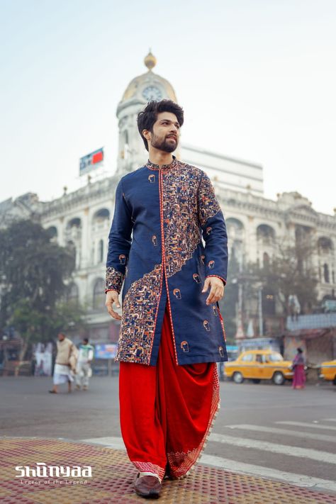 ASTITVA by Shunyaa, Legacy of the Legend. On Model : Mediterranean blue Achkan on raw silk. Uniquely done many faces embroidery work, a tribute to India and her rich heritage in asymmetric rendition. Teamed up with rust embroidered dhoti. A perfect ensemble for Indian Groom. Visit our store to experience the craftmanship of India. Join us at Shunyaa @ 7044393333 (WhatsApp/Call) Address: 38, CB Block, Sector 1, Salt Lake, Kolkata - 700064 https://maps.app.goo.gl/bC2n8q1LXh9GWQdr7 Red Men Outfit, Indian Wedding Suits Men, Wedding Dresses Men Indian, Indian Illustration, Men Kurta, Kurta Men, Mens Kurta Designs, Lakshmi Images, Wedding Outfit Men