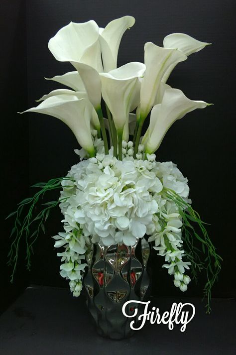 Tall floral arrangement with calla lilly and hydrangea and wisteria in whites Wisteria Arrangement Vase, Calla Lily Arrangement Ideas, White Modern Floral Arrangement, Lilly Arrangements, Lilly Flower Arrangements, Calla Lillies Centerpieces, Flower Arrangements For Table, Calla Lily Arrangement, Lily Arrangement