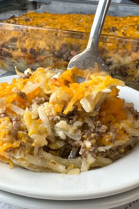 Fork in a plate of cheesy ground beef hash brown casserole Hashbrown Casserole With Meat, Shredded Potatoes And Ground Beef, Cheeseburger Casserole Hashbrown, Hamburger Recipes With Hashbrowns, Ground Beef With Hashbrowns, Hamburger Supper Ideas Ground Beef, Simple Ground Beef Casseroles, Hamburger Hashbrown Casserole Recipes Easy, 5 Ingredient Hamburger Casserole