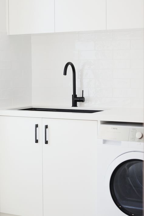 The light and bright laundry at our Brighton project was achieved through the use of white 2pac joinery, white reconstituted stone benchtop and white subway tiles. We paired this with matt black tapware, a black undermount sink and black handles to create a striking monochromatic look. Black Laundry Sink, Black Undermount Sink, Black And White Laundry, Full House Renovation, Black Tapware, Laundry Renovation, Design Studio Interior, Stone Benchtop, House Renovation Projects