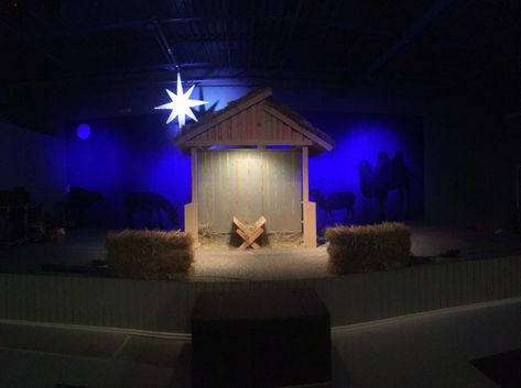 CJ Walters from Revive in Dry Ridge, KY brings us this Christmas stable. From CJ: This is the manger set we built for our Children’s Christmas play this year. The need was just a typical nativity scene, so we decided to keep it simple and build a stable attached to our drum cage, add a star and paint some animals. The back wall of our stage was painted a dark blue, we then projected a few animals onto the wall and painted them black to get the silhouette look. A Star of David was projected on... Stable For Christmas Play, Christmas Play Set Design, Nativity Sets Display, Nativity Backdrop, Childrens Ministry Christmas, Christmas Stage Decorations, Drum Cage, Christmas Stage Design, Nativity Play