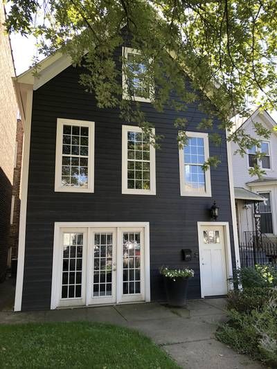 Dark Brown Ranch House Exterior, Dark Grey Cottage Exterior, Dark Cape Cod House Exterior, Dark Exterior Brick House, Dark Painted Houses, Black House Siding, Black House Green Door, Black House White Windows, Charcoal Grey House Exterior