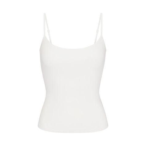 A classic cami in the internet’s favorite lounge fabric. This ultra-comfy top is made with our addictively soft, slinky ribbed fabric for flattering comfort on the couch or on the go. Features an interior shelf bra with underbust elastic for light bust support, a chic scoop neck, and adjustable back straps. Hits below the natural waist and fits true to size. Given the semi-sheer nature of this colorway, we recommend wearing with a SKIMS foundation in your go-to neutral shade. Neutral Tank Tops, Simple White Top, Fame Clothes, White Spaghetti Strap Top, White Cami Top, Basic Clothes, At Home Outfits, White Tube Top, White Spaghetti Strap