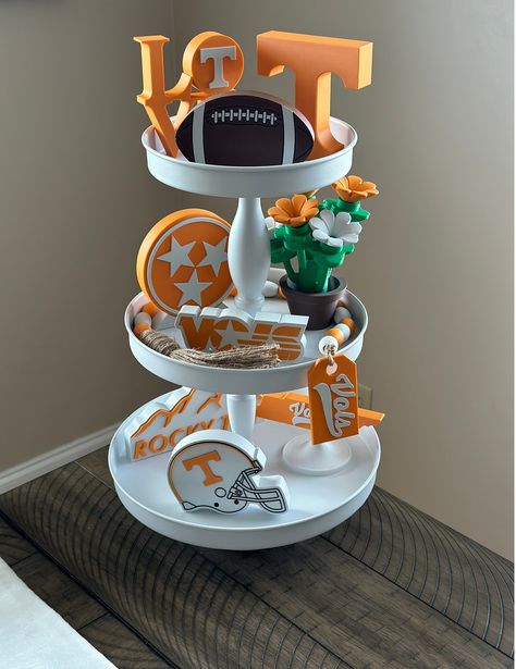 Tennessee Vols / Volunteers Tier Tray Decor - Desk and Table Art Show your Tennessee Vol pride and support Big Orange with these custom 3D Printed pieces. Power T - 4.5" wide/tall x 1" thick TN Volunteers Bead Garland - 30" long including jute tassle and tag Football - 5" wide x 3.15" tall x 0.75" thick LOVE with T Cutout/Raised - 4.15" wide x 4.5" tall x 0.8" thick VOLS Logo - 5.3" wide x 1.85" tall x 0.75" thick Tri-Star Logo with Base - 4.6" wide x 4.95" tall x 0.85" thick Lego-Inspired Flowe Tailgate Table Decorations, Tennessee Vols Party, Tennessee Football Decor, Tennessee Decor, Tennessee Crafts, Tn Vols Football, Desk And Table, Tailgate Table, Tennessee Christmas