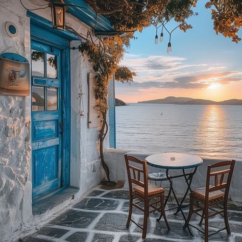 A quaint cafe corner with a stunning view of the sunset over tranquil sea waters. Quaint Cafe, Cafe Corner, Seaside Cafe, Seaside Sunset, Sunset View, Blue Door, Coastal Towns, Sunset Views, Wooden Chair