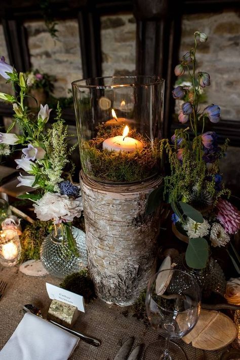 a woodland wedding centerpiece of bold blooms, greenery, moss and a tree stump with a candle and moss Green Moss Wedding Decor, Moss And Roses Centerpieces, Moss And Wood Table Decor, Small Enchanted Forest Wedding, Mossy Wedding Bouquet, Woodland Themed Wedding Decorations, Spanish Moss Wedding Centerpiece, Moss Party Decor, Moss Centrepiece