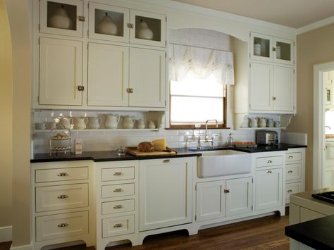 This quaint cottage kitchen features antique white Shaker cabinets, black countertops and a white subway tile backsplash. A white apron-front sink adds a farmhouse-feel to the space. Antique White Kitchen Cabinets, Antique Kitchen Cabinets, Antique White Cabinets, White Kitchen Traditional, Used Kitchen Cabinets, White Shaker Kitchen Cabinets, Vintage Kitchen Cabinets, Antique White Kitchen, Kitchen Cabinets For Sale