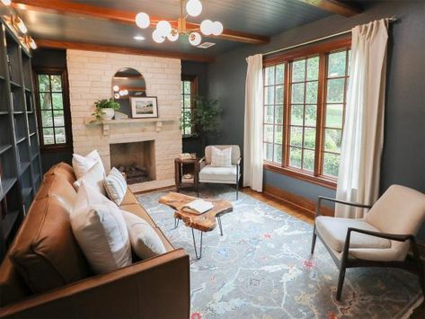 To make her clients' small and disjointed living room feel bigger, No Demo Reno host Jenn Todryk used a moody gray on the ceiling, walls and built-ins to tie every element together. An area rug with lighter gray tones picks up on the paint color and makes the room feel more airy. The creamy stone fireplace, white curtains and matching white chairs provide a break from the dark walls and ceiling. Jenn Todryk, No Demo Reno, Houses In America, Hgtv Star, Hgtv Dream Home, Decorating Advice, Dark Walls, Outdoor Kitchen Design, Living Room Grey