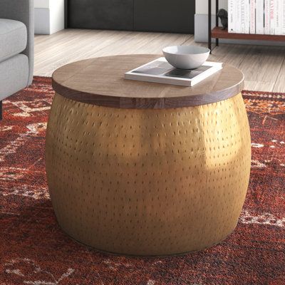 This coffee table with storage blends textures and hues to create an artisanal look for your living room. Its size makes it an easy option for space-conscious rooms, and it doubles up as a side table for larger furniture ensembles. With a curved, drum silhouette, it has a hammered metal base with a round solid wood top. The top comes in a rich mocha finish that highlights the wood's natural grain. Lift the top to reveal space to keep blankets, toys, or pillows. Convenient yet distinctive, this t Glam Coffee Table, Drum Coffee Table, Hammered Iron, Metal Drum, Table For Small Space, Round Storage, Coffee Tables For Sale, Austin Design, Table With Storage