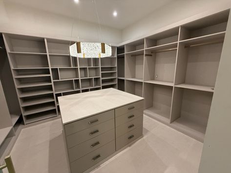 Spacious neutral color walk-in closet with island. Walk-in Closet Island Ideas, Corner Walk In Closet, His And Hers Walk In Closet Design, Walk In Closet With Island, Big Walk In Closet, Closet With Island, A Walk In Closet, Closet Island, Walk In Closet Design